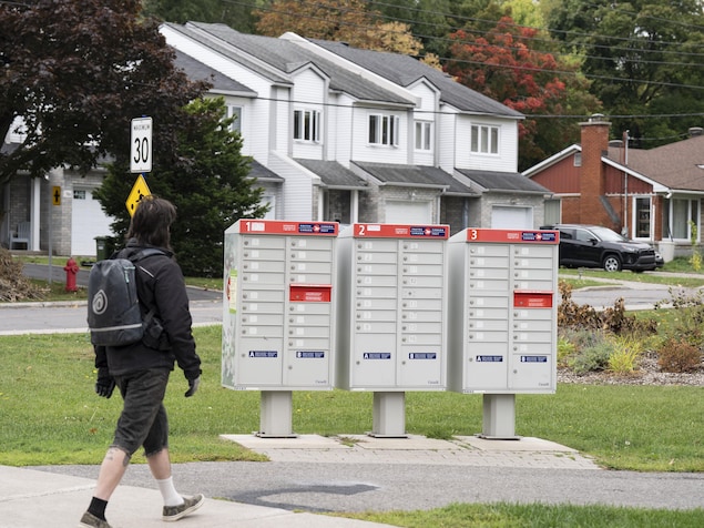 Un homme marche près des boîtes postales communautaires.