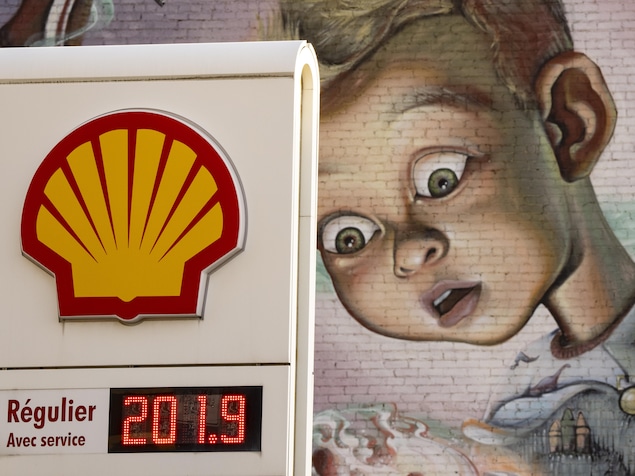 Un station-service affichant le prix de l'essence avec une murale à l'arrière-plan.