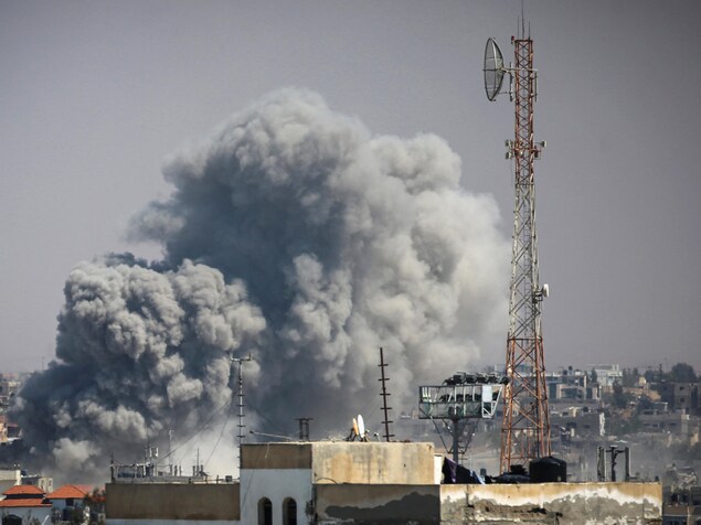 Une épaisse volute de fumée s'échappe d'un quartier de Rafah, au milieu d'immeubles, à proximité d'un pylône électrique.