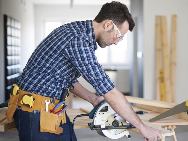 Un homme coupe une planche de bois. Un homme coupe une planche de bois.