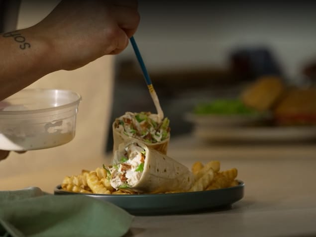 Une personne retouche un wrap avec un pinceau et de la peinture blanche.