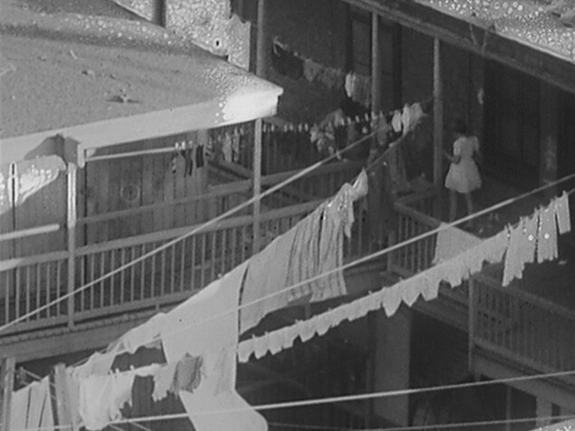 Un enfant sur la terrasse d'une maison ouvrière avec du linge pendu partout pour sécher. Un enfant sur la terrasse d'une maison ouvrière avec du linge pendu partout pour sécher.