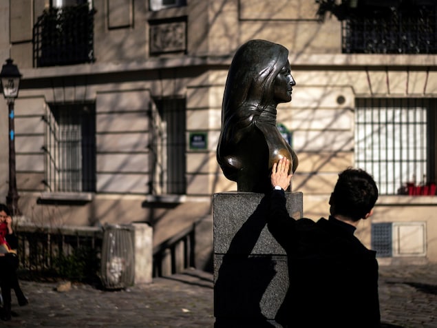 Un homme touche la poitrine de la statue Dalida.