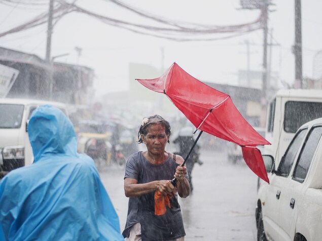 Une femme tente de maintenir en place son parapluie, emporté par le vent sous la pluie. Une femme tente de maintenir en place son parapluie, emporté par le vent sous la pluie.