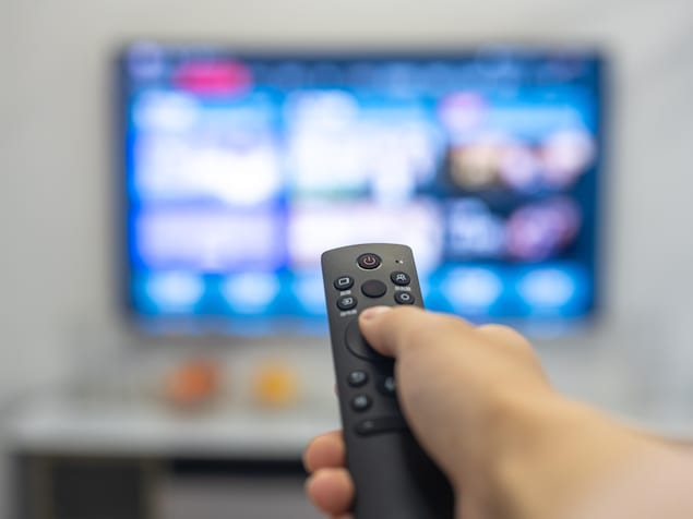 Une télécommande devant une télévision.
