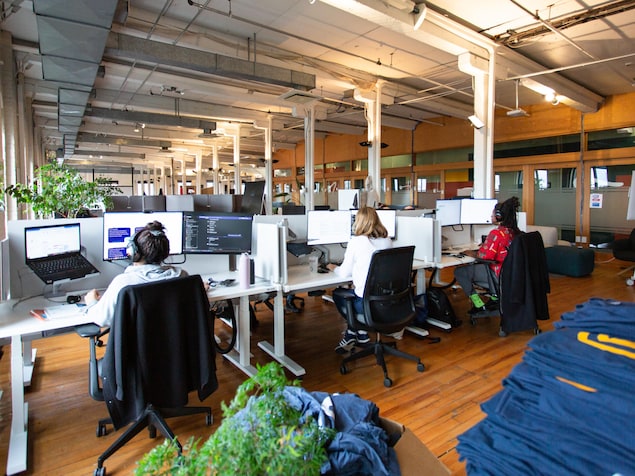 Des personnes travaillent à l'ordinateur dans un espace de bureau ouvert. 