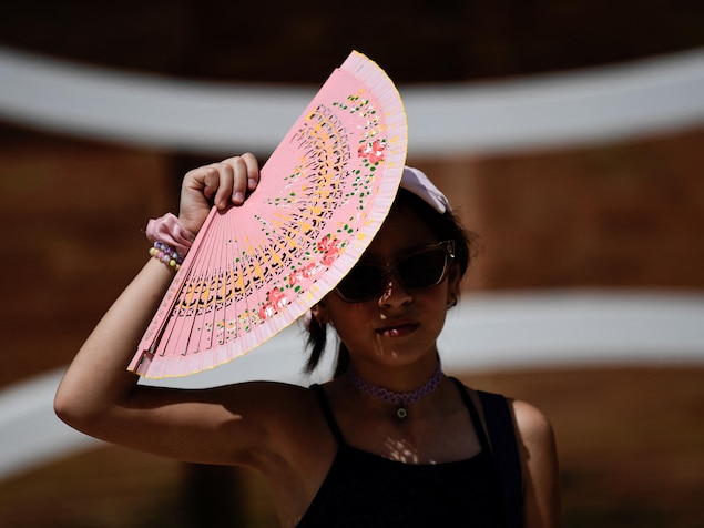 Une femme se protège du soleil avec un éventail.
