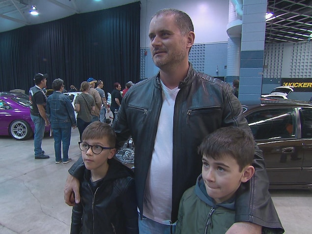 Un père avec ses deux fils dans un salon d'automobiles modifiées. Un père avec ses deux fils dans un salon d'automobiles modifiées.