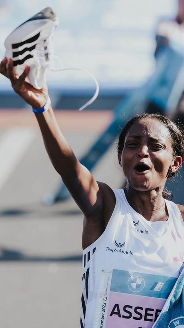 La marathonienne éthiopienne Tigist Assefa tient une espadrille d'Adidas dans ses mains après une course.
