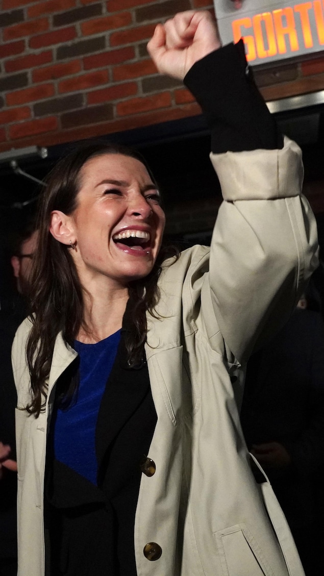 Ariane Boyer entre, toute sourire, à son rassemblement pour célébrer la victoire, poing dans les airs.