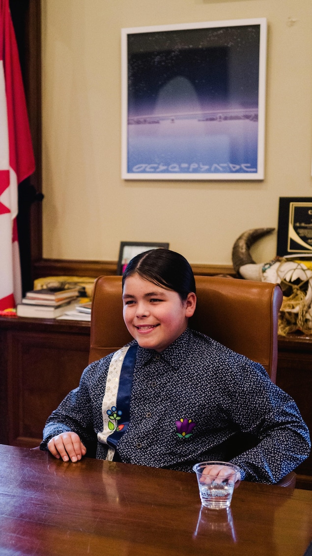 Le jeune Théo Osborne qui sourit alors qu'il est assis au bureau du premier ministre du Manitoba, Wab Kinew.