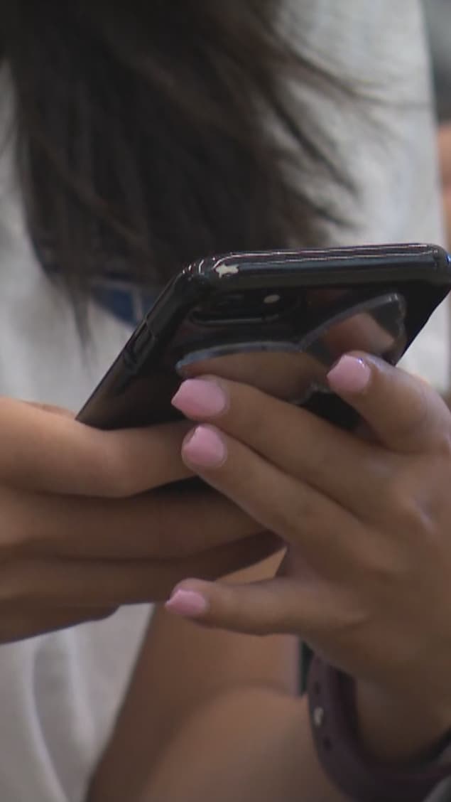 Une élève tient un cellulaire dans les mains dans une école à Woodbridge, le 3 septembre 2024.
