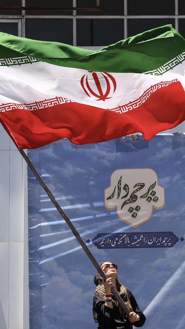Une femme iranienne brandit le drapeau national à Téhéran, le 15 juin 2026.
