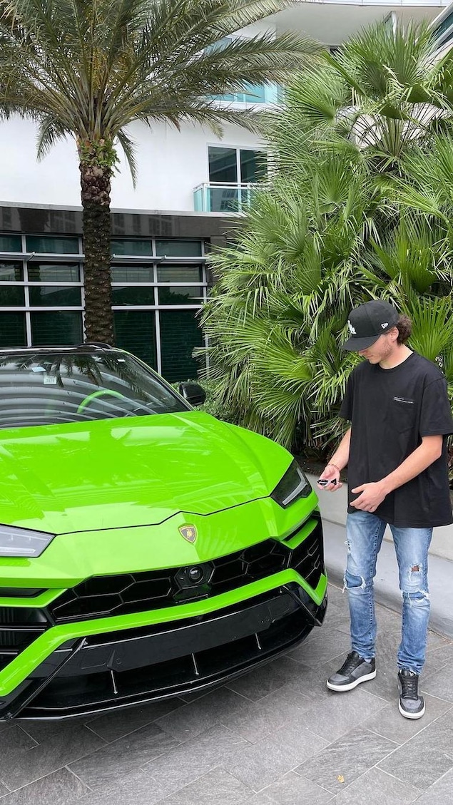 Aiden Pleterski se tient debout à côté d'une voiture verte de marque Lamborghini et des palmiers à Miami en Floride. 