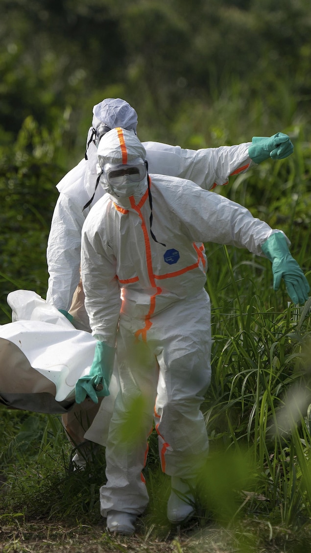 Des travailleurs funéraires en vêtements de protection portent les restes d’un homme mort d'Ebola. 