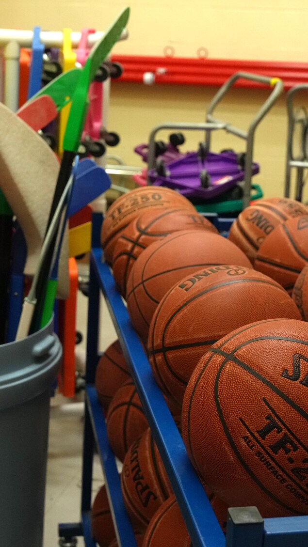 Des ballons de basketball et des bâtons de hockey dans l'entrepôt d'un gymnase d'une école primaire de Toronto, en Ontario, le 9 janvier 2024.