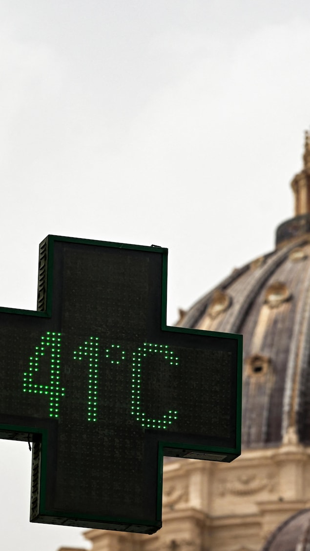 Un écran devant une pharmacie indiquant une température extérieure de 41 °C.