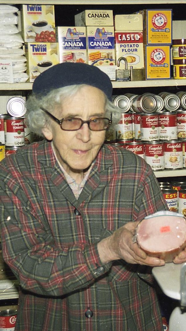 Une femme dans une vieille épicerie tient un jambon.