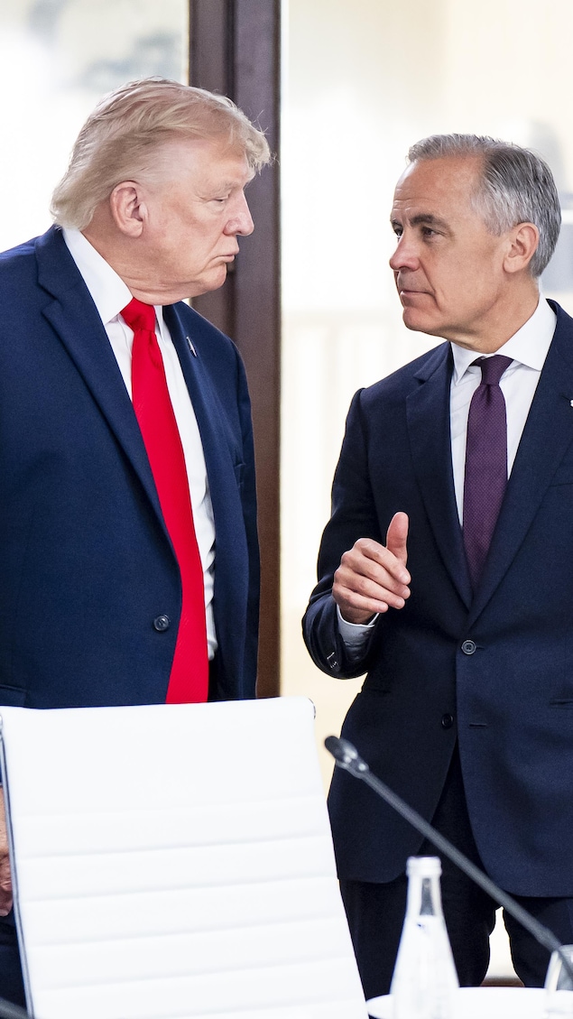 Donald Trump et Mark Carney discutent debout près d'une table de conférence, devant une vitre arborant le logo du G7.