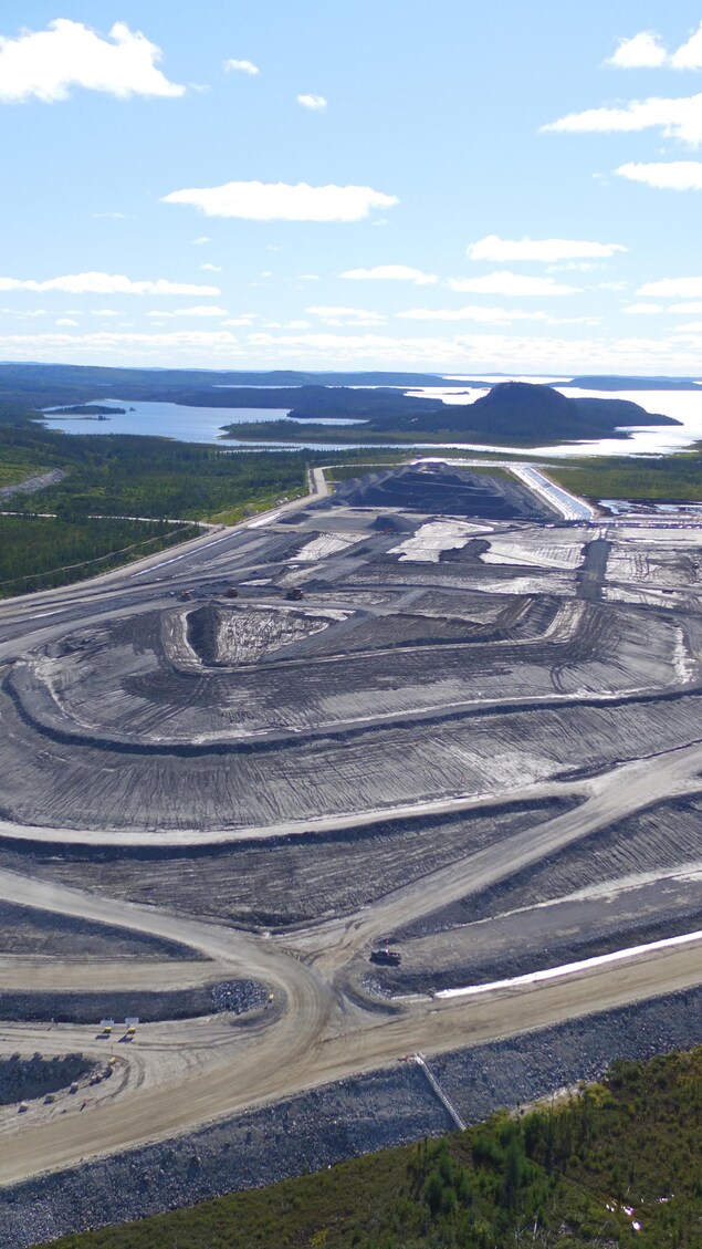 Photo aérienne d'une mine, entourée de chemins et d'un lac au loin.