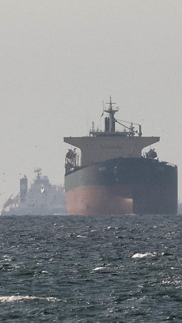 Des gros navires pétroliers sur l'eau, photographiés de loin, sous un ciel voilé.