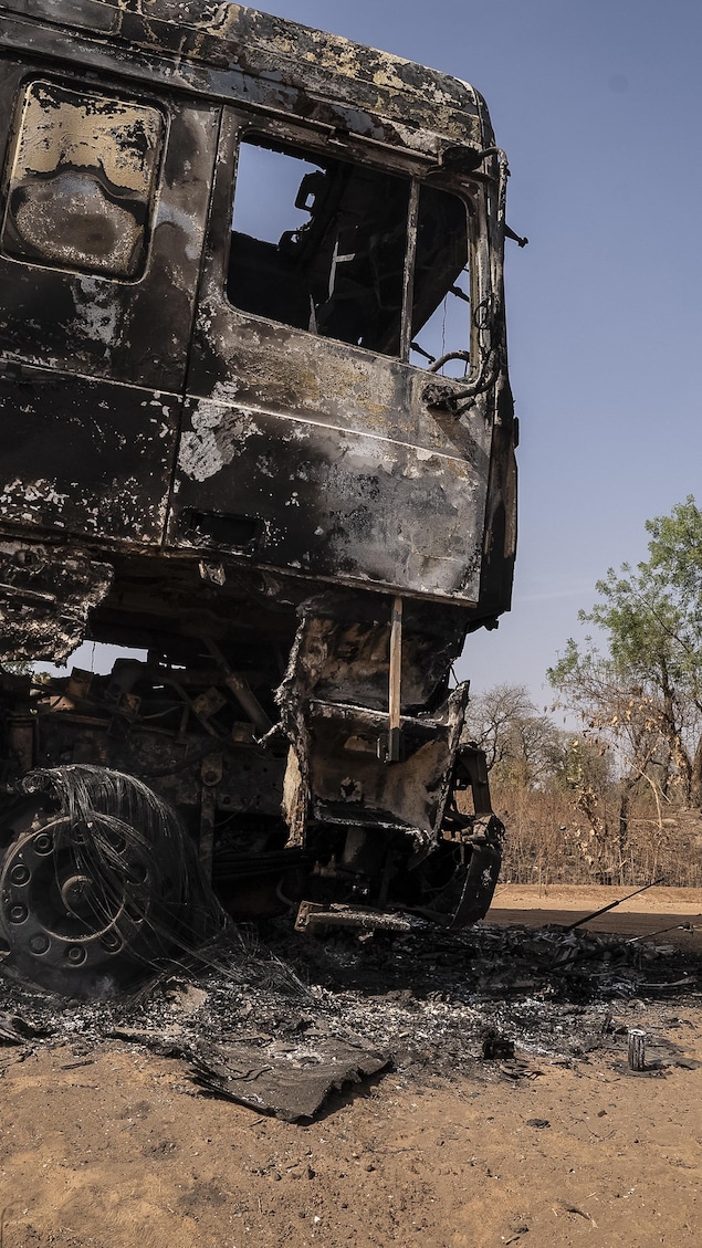 Des hommes passent devant un camion incendié après une attaque à Woro, dans l'État de Kwara, le 5 février 2026. 