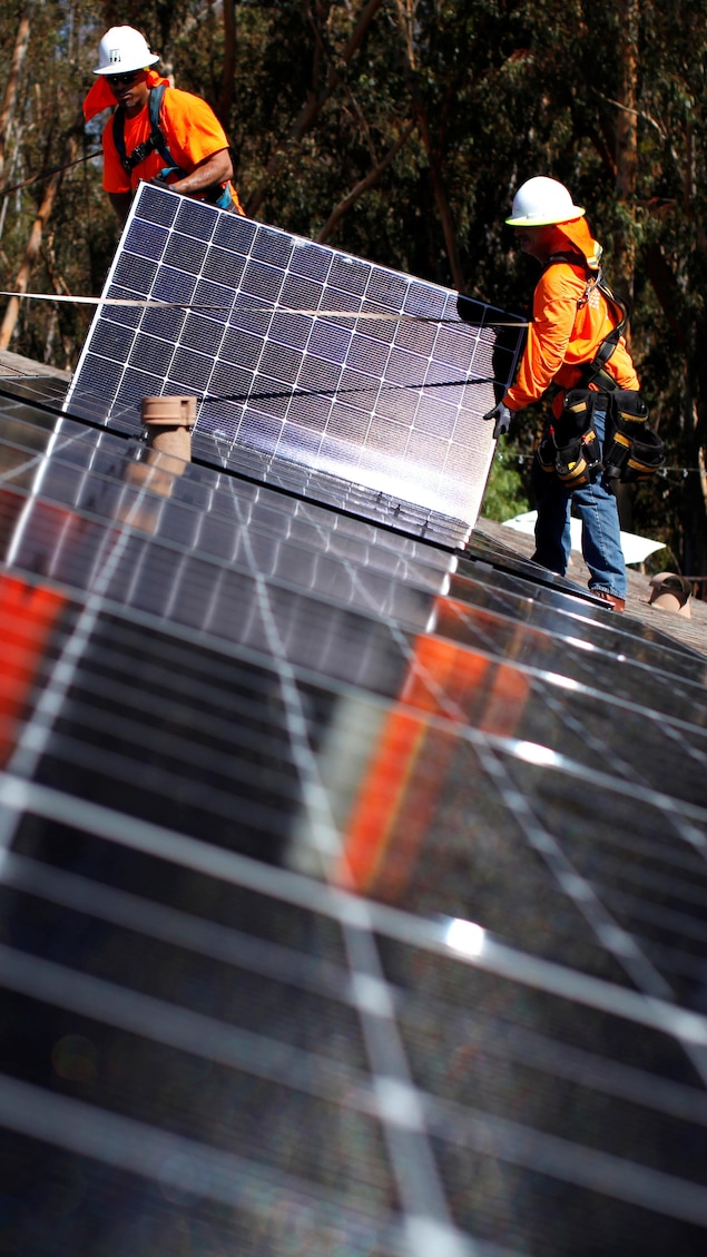 Des travailleurs installent des panneaux solaires sur un toit.