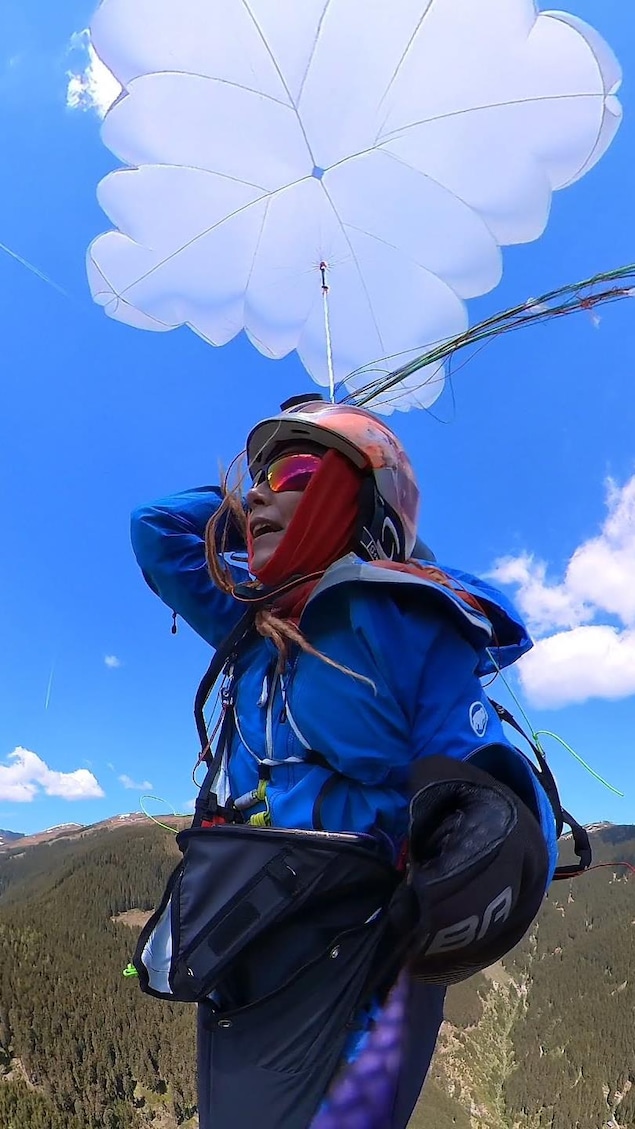 Une femme est suspendue dans les airs à un parachute.