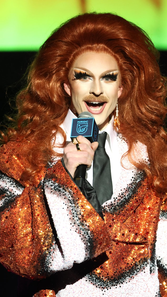 Une drag queen parle dans un micro.