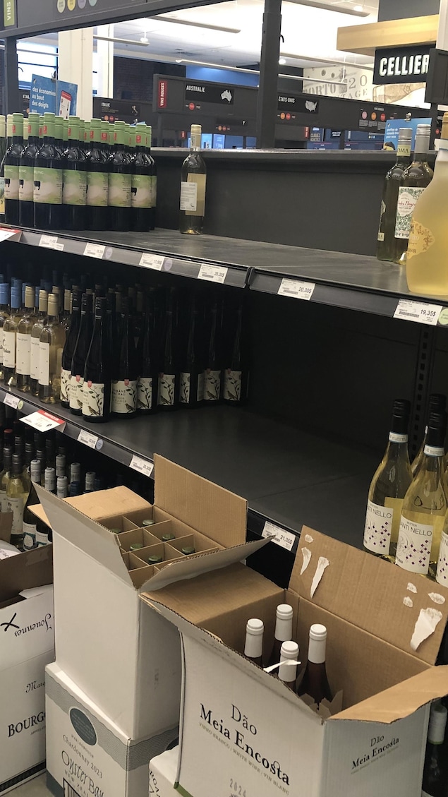 Des cartons pleins au pied de tablettes en partie vides.