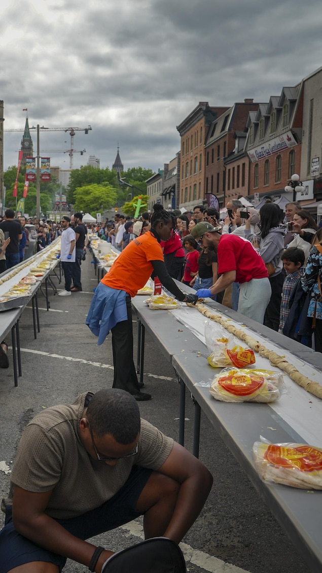 Des shawarmas sont roulés et alignés sur deux tables par des bénévoles.