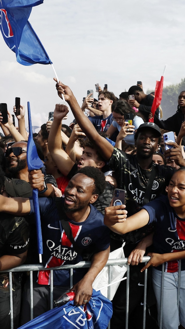 Des partisans derrière une barrière tentent de prendre en photo les joueurs de l'équipe.