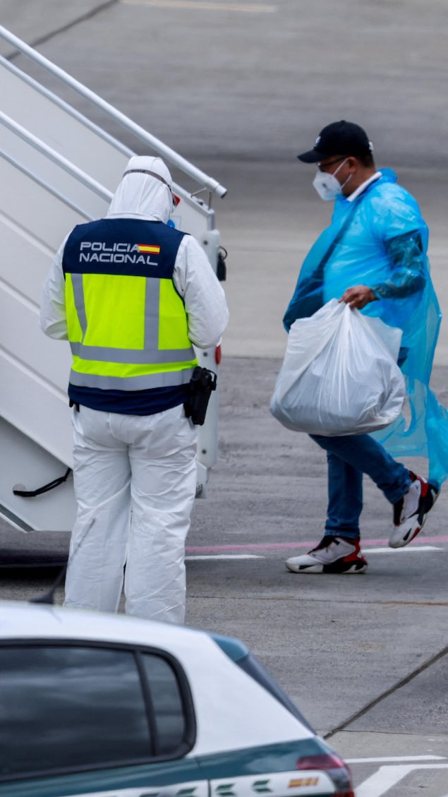 Un homme portant de l'équipement de protection individuelle s'apprête à monter dans un avion.