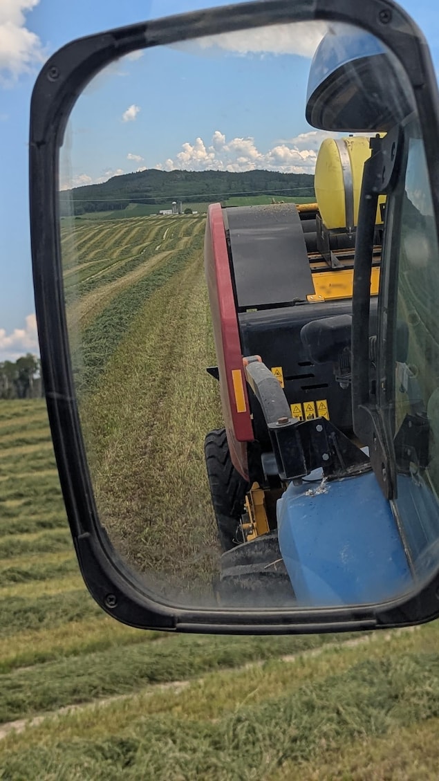 Photo d'un miroir du tracteur dans lequel on voit le paysage agricole.