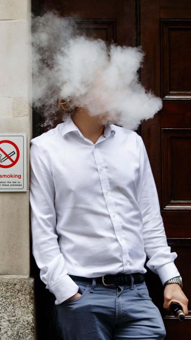 Un fumeur est englouti par les vapeurs alors qu'il fume une machine à vapotage électronique à l'heure du déjeuner dans le centre de Londres.