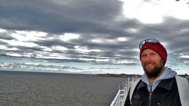 Éros D'Astous pose devant le fleuve Saint-Laurent le regard confiant