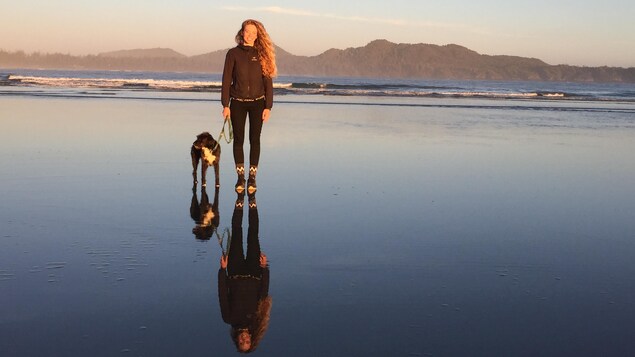 Sophie pose avec son chien, Peepa sur une plage de Tofino.