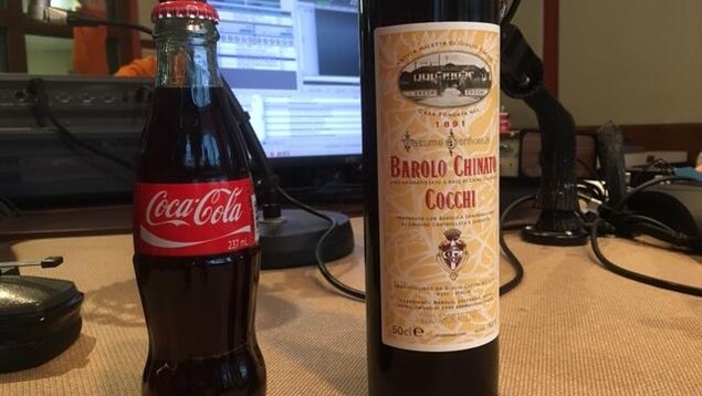 Une bouteille de Coca-Cola et une bouteille de Barolo Chinato Cocchi sur une table dans un studio