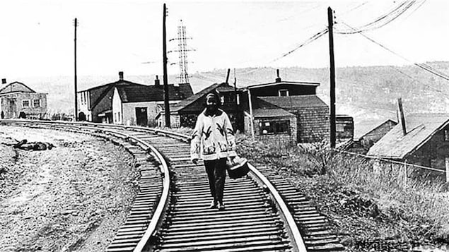 Une femme marche le long d'une voie ferrée.