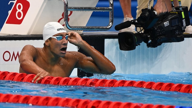 Ahmed Hafnaoui regarde au loin d'un air surpris après sa victoire.