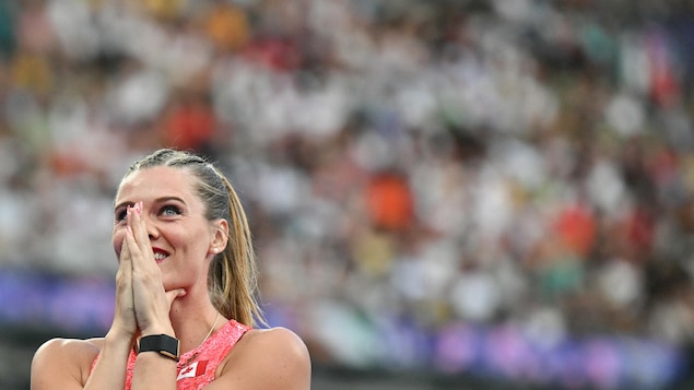 Une perchiste joint les mains devant son visage après avoir réalisé un beau saut aux Jeux olympiques.