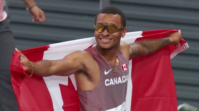 Andre De Grasse arbore un drapeau canadien suivant l'obtention de la troisième place.