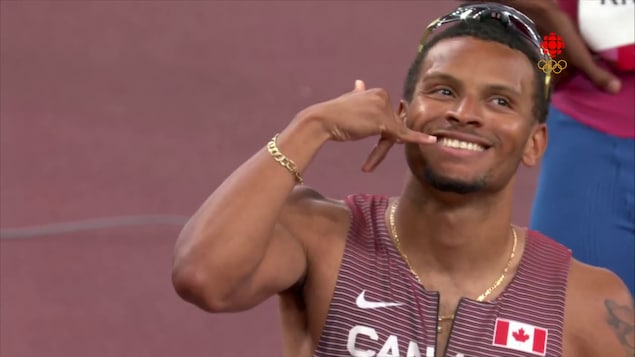 Andre De Grasse fait un shaka avec sa main droite.