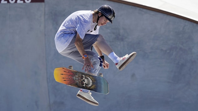 Andy Anderson effectue un saut avec sa planche à roulettes. La planche est en train de virevolter sous l'athlète.