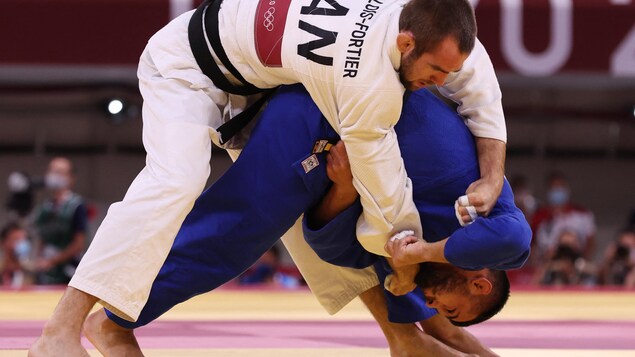Un judoka, en blanc, est sur le dos de son adversaire pendant un combat.