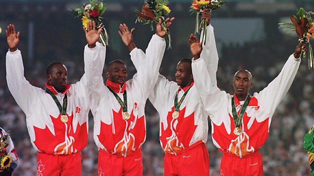 Quatre coureurs canadiens célèbrent leur médaille d'or sur le podium.