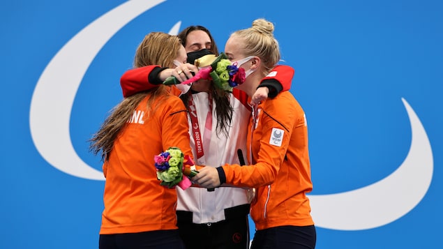 Aurélie Rivard enlace deux athlètes des Pays-Bas Chantalle Zijderveld et Lisa Kruger sur le podium.