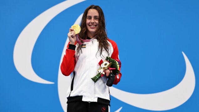 Aurélie Rivard pose fièrement, médaille d'or au cou, sur la première marche du podium paralympique à Tokyo. 