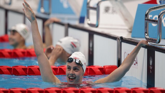 Aurelie Rivard lève un bras pour célébrer sa victoire dans la piscine du Centre aquatique de Tokyo. 