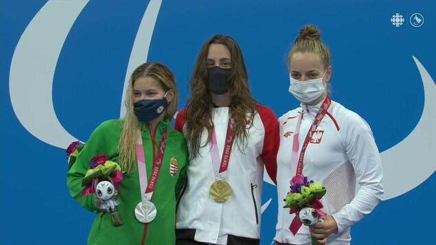 Trois femmes posent enlacées avec leur médaille au cou.
